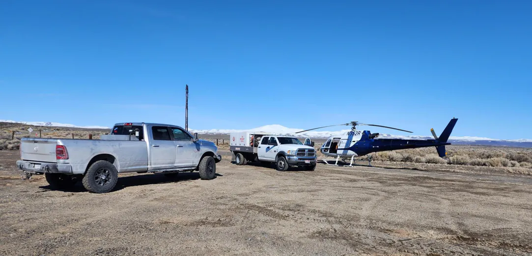 Mining vehicles and a helicopter staged at a remote exploration site
